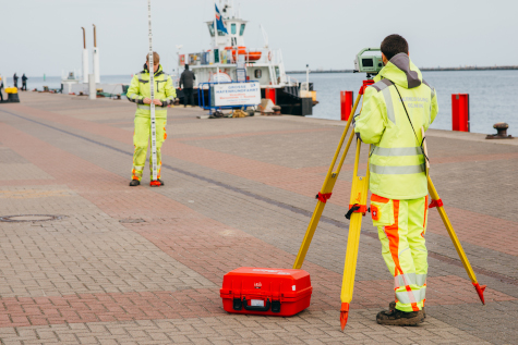 Durchführung von einem Nivellement durch einen Vermessungsingenieur und einen Vermessungstechniker im Hafen von Rostock